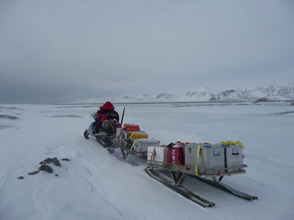 Snøscooter med tilhengere i snøkledt landskap, Svalbard