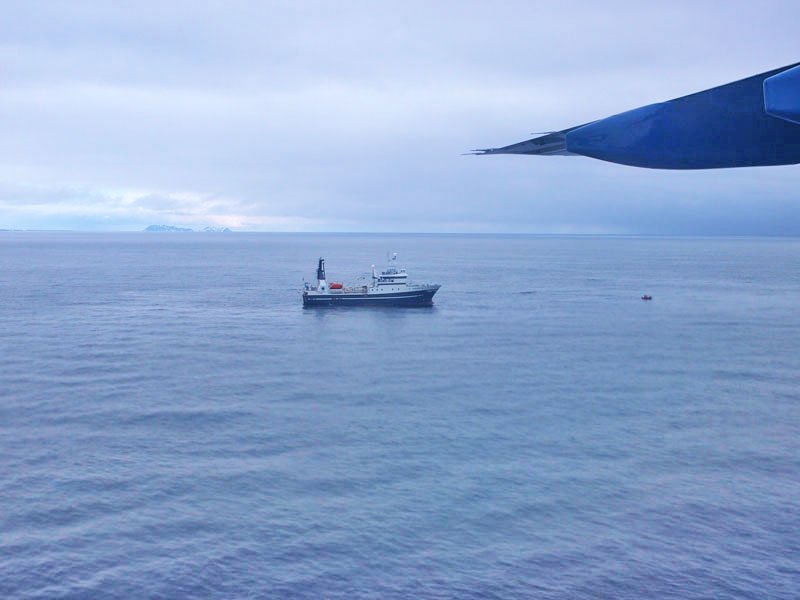 Del av flyvinge og båt på havet i bakgrunnen