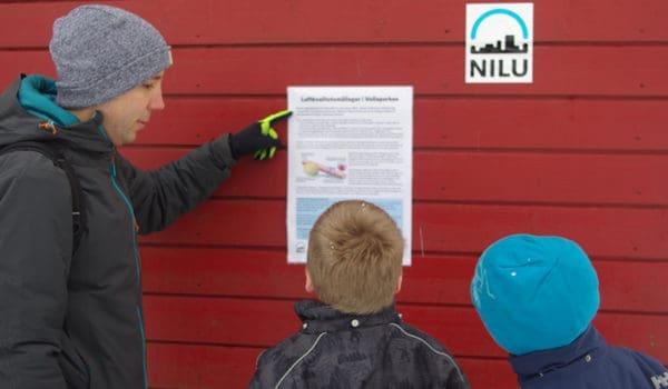 Frank Dauge informerer to skoleelever foran NILUs målebu i Vollaparken